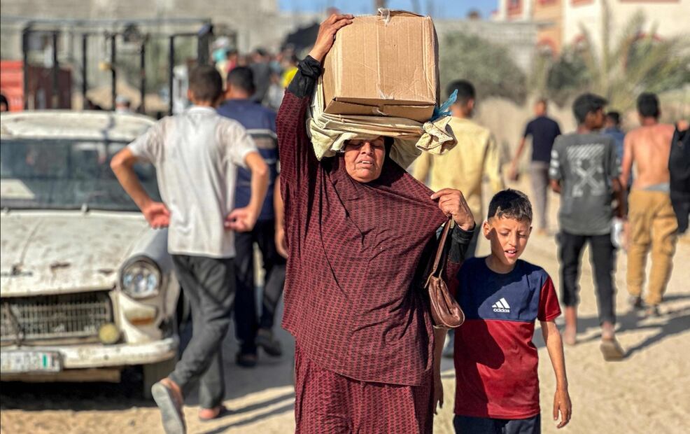 Una madre y su hijo caminan con paquetes de alimentos de una fundación respaldada por Estados Unidos que se compromete a distribuir ayuda humanitaria en Rafah, al sur de la Franja de Gaza, el 27 de mayo de 2025. Foto: AFP