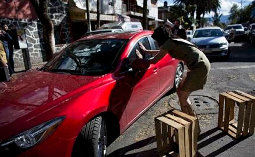 Arturo Hernández, wearing a dress and heels, implores a double-parked driver to move his car from a clogged street outside the ITESM in Mexico City. (Photo: AP) 