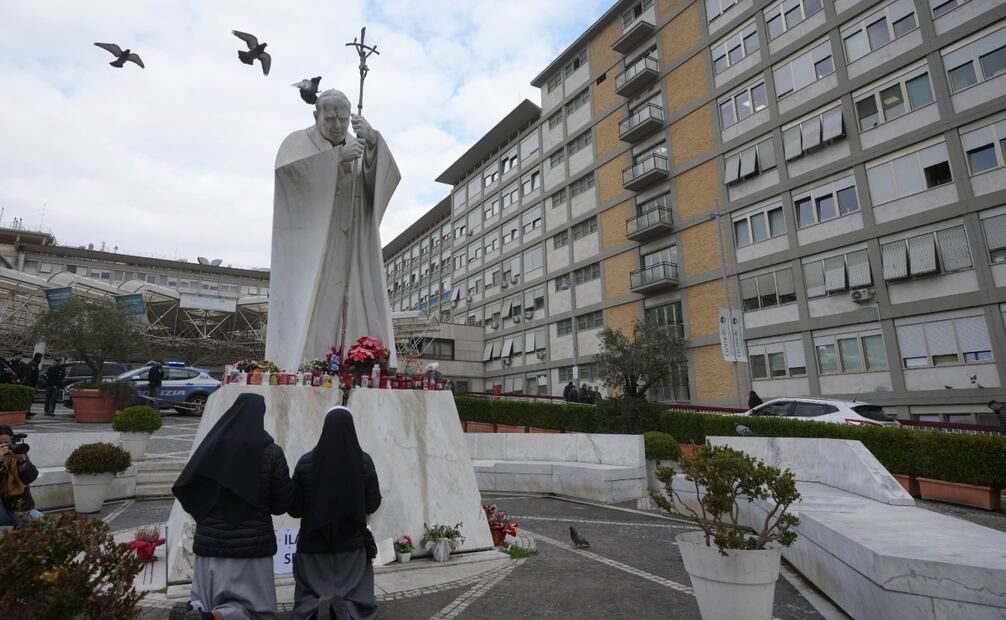 Dos monjas rezan frente a una estatua de san Juan Pablo II frente al hospital policlínico Agostino Gemelli, en Roma. Foto: AP
