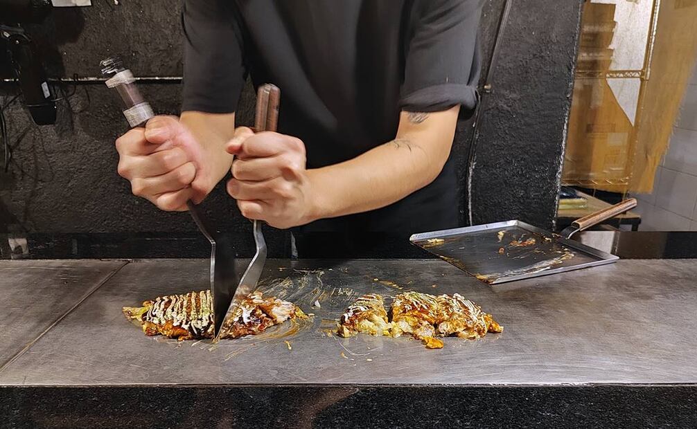 Tras salir de la plancha del chef, usan una gran espátula para llevar el okonomiyaki al frente al asiento del cliente y por último lo rebanan. Si se elige una de las mesas al exterior, el alimento llegará emplatado. Foto: Raúl Fontecilla/EL UNIVERSAL.