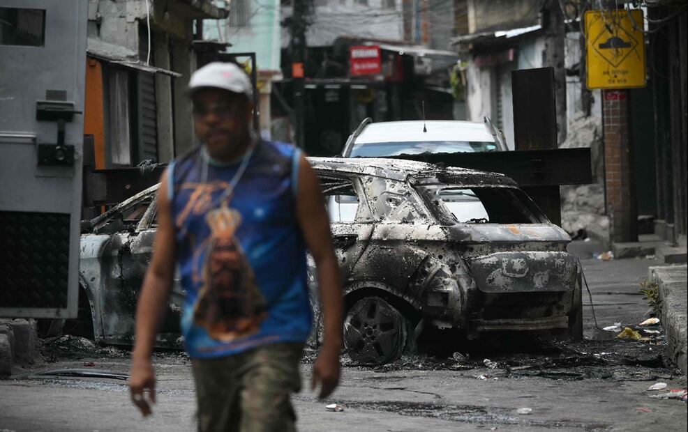 Un hombre pasa junto a un coche incendiado que sirvió de barricada en la favela Vila Cruzeiro, durante la Operación Contención en Río de Janeiro. el 28 de octubre de 2025. Foto: AFP