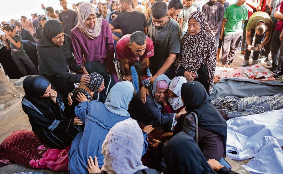 Palestinos junto a los cuerpos amortajados de sus familiares fallecidos en los ataques israelíes contra la Ciudad de Gaza, en el hospital Al-Shifa, el martes pasado. Foto: Omar Al-Qattaa / AFP